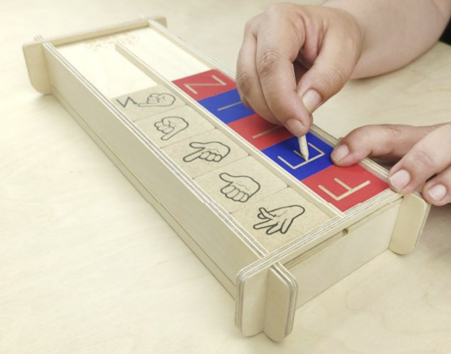 Manos de un niño colocando las cartas del alfabeto móvil en la caja de ensambles